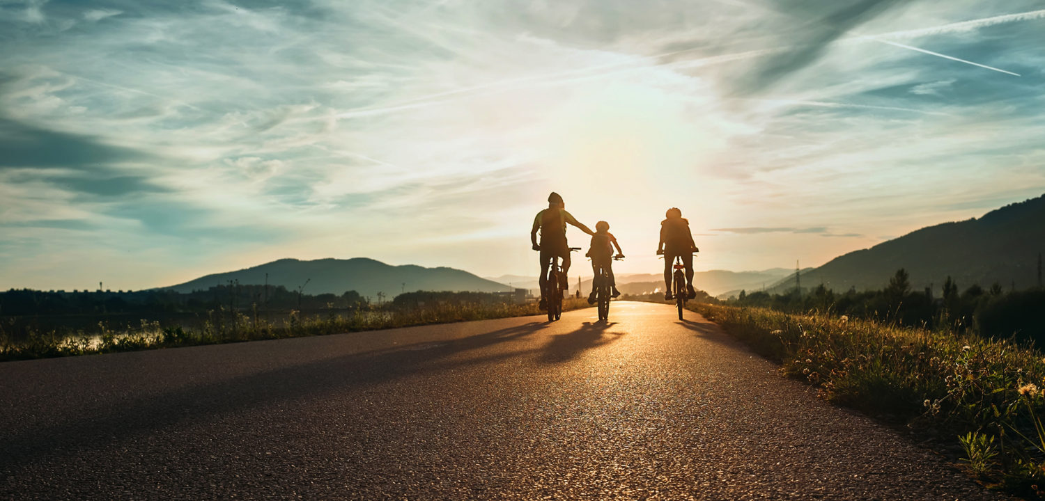 Cyclists,Family,Traveling,On,The,Road,At,Sunset
